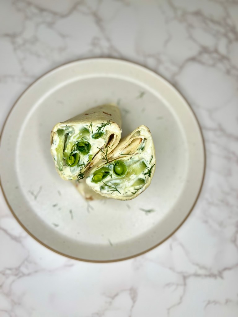 Veggie Wrap with Basil Tzatziki that's been cut in half and garnished with dill on a white plate