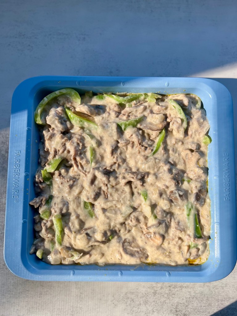 All of the filling ingredients for Philly Cheesesteak Casserole in a baking dish getting ready for the oven