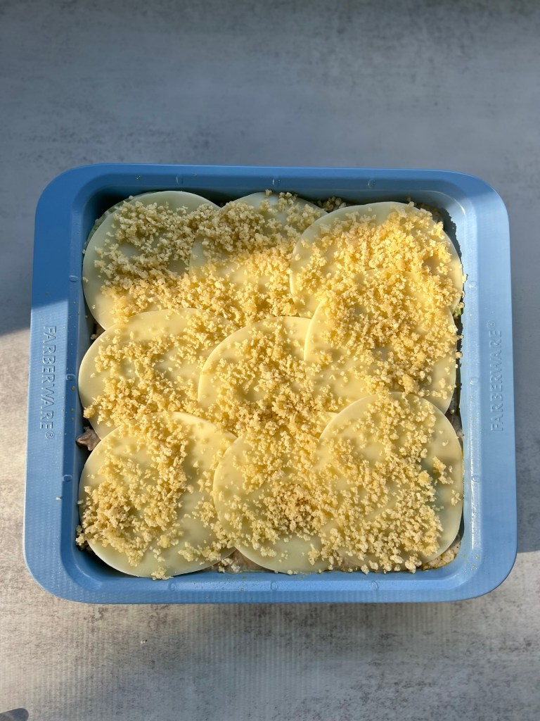 Philly Cheesesteak Casserole in a baking dish with provolone and a breadcrumb topping about to go in the oven