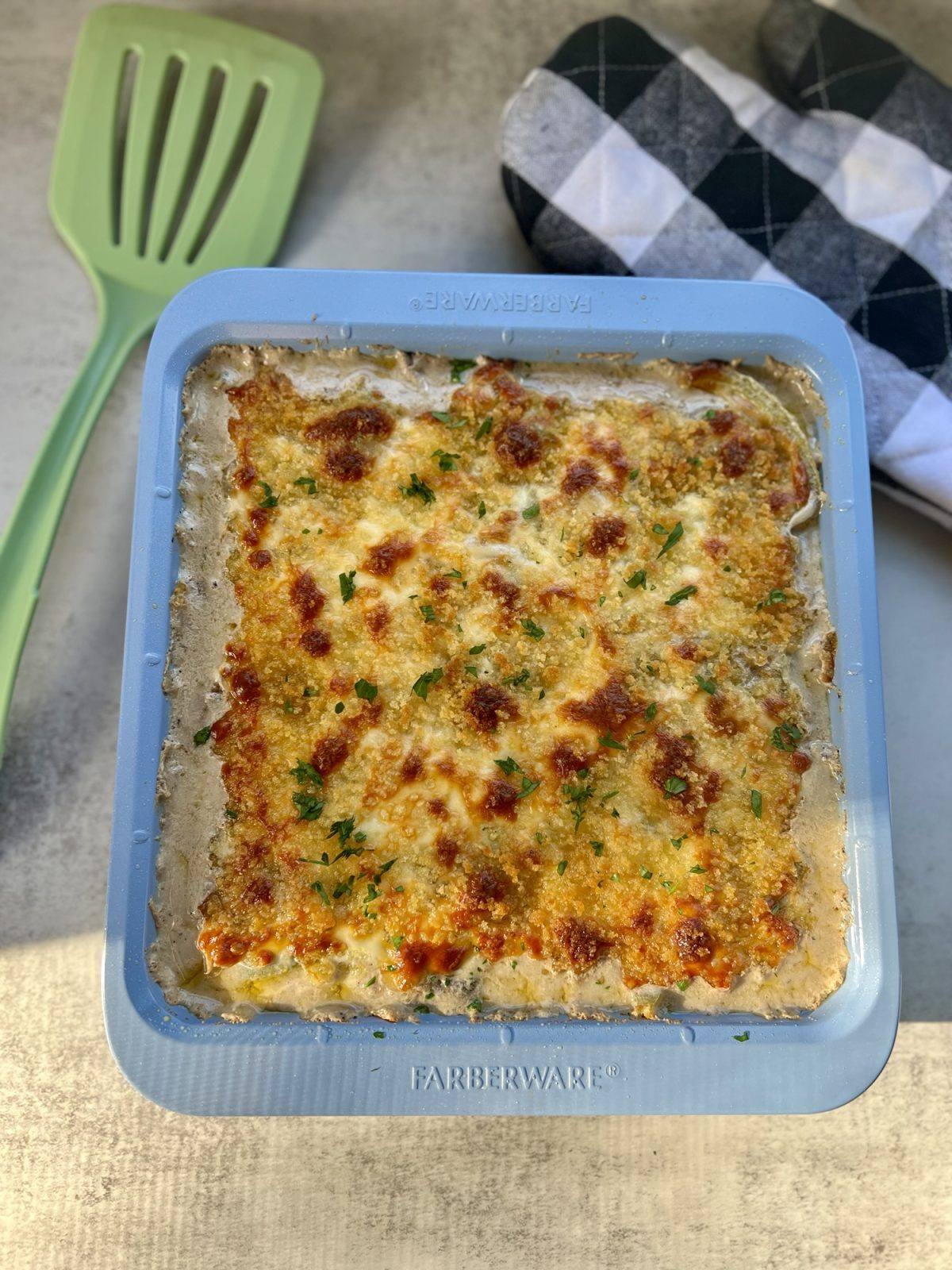 Philly Cheesesteak Casserole in a baking dish with a spatula and oven mit nearby