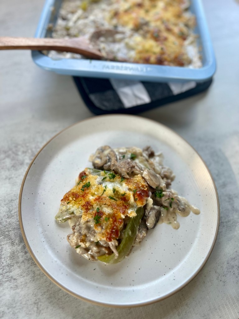 Philly Cheesesteak Casserole that's been scooped out of the baking dish and put onto a white plate