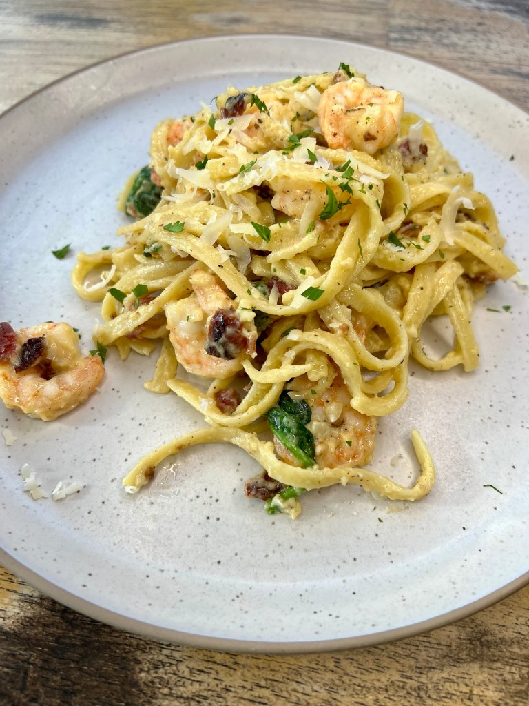 Shrimp carbonara on a white plate on a wooden table
