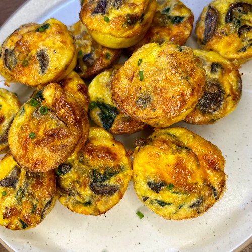 Mushroom Spinach egg cups on a white plate on a wooden countertop