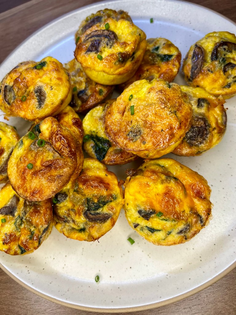 Mushroom Spinach egg cups on a white plate on a wooden countertop