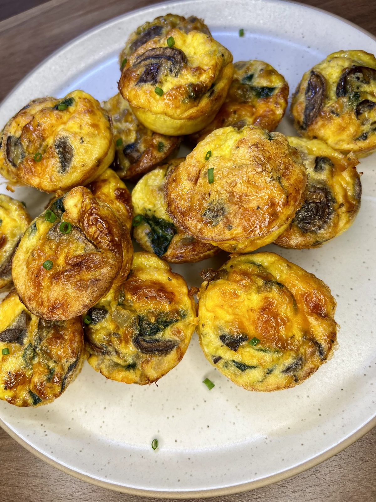 Mushroom Spinach egg cups on a white plate on a wooden countertop