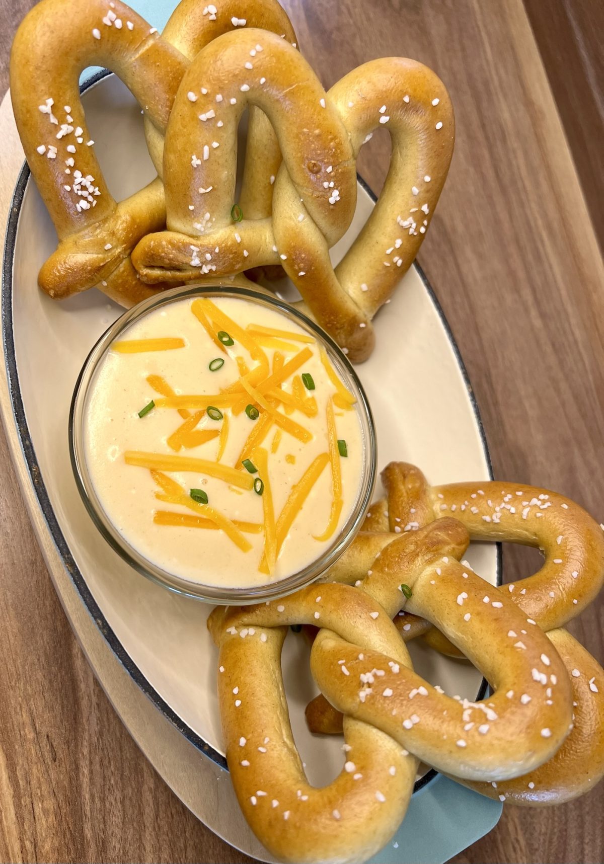 Beer cheese served with some pretzels in a serving dish on a wooden counter