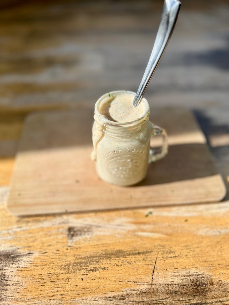 Chipotle Aioli in a mason jar with a spoon sticking out of it on a wooden table