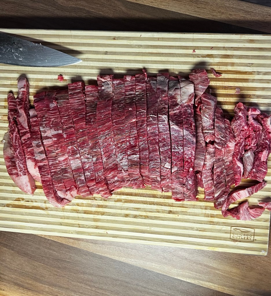 SRF flank steak that's been thinly sliced on a wood cutting board