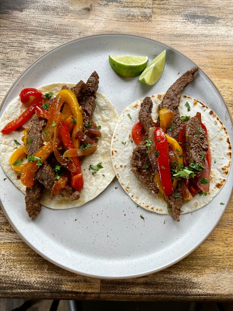 Flank Steak Fajitas on a white plate on a wooden table