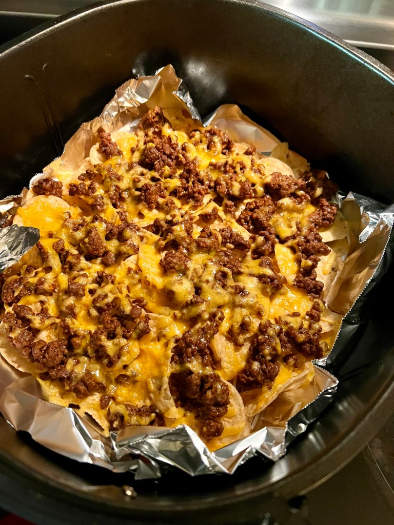 Air fryer nachos in an air fryer basket before any garnishes are put on
