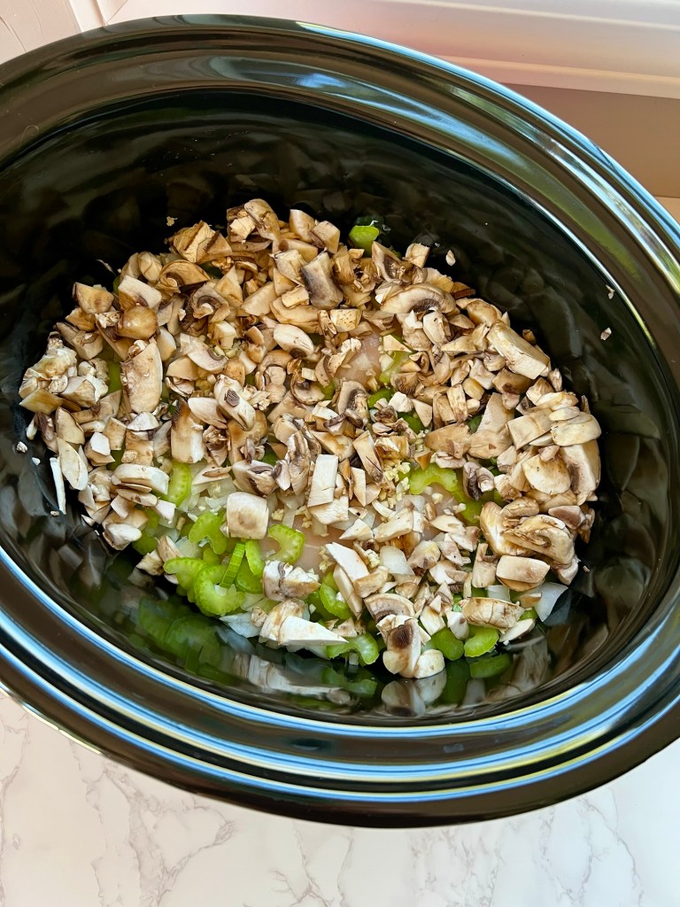 Mushrooms, onion, garlic, chicken, and celery in a crockpot