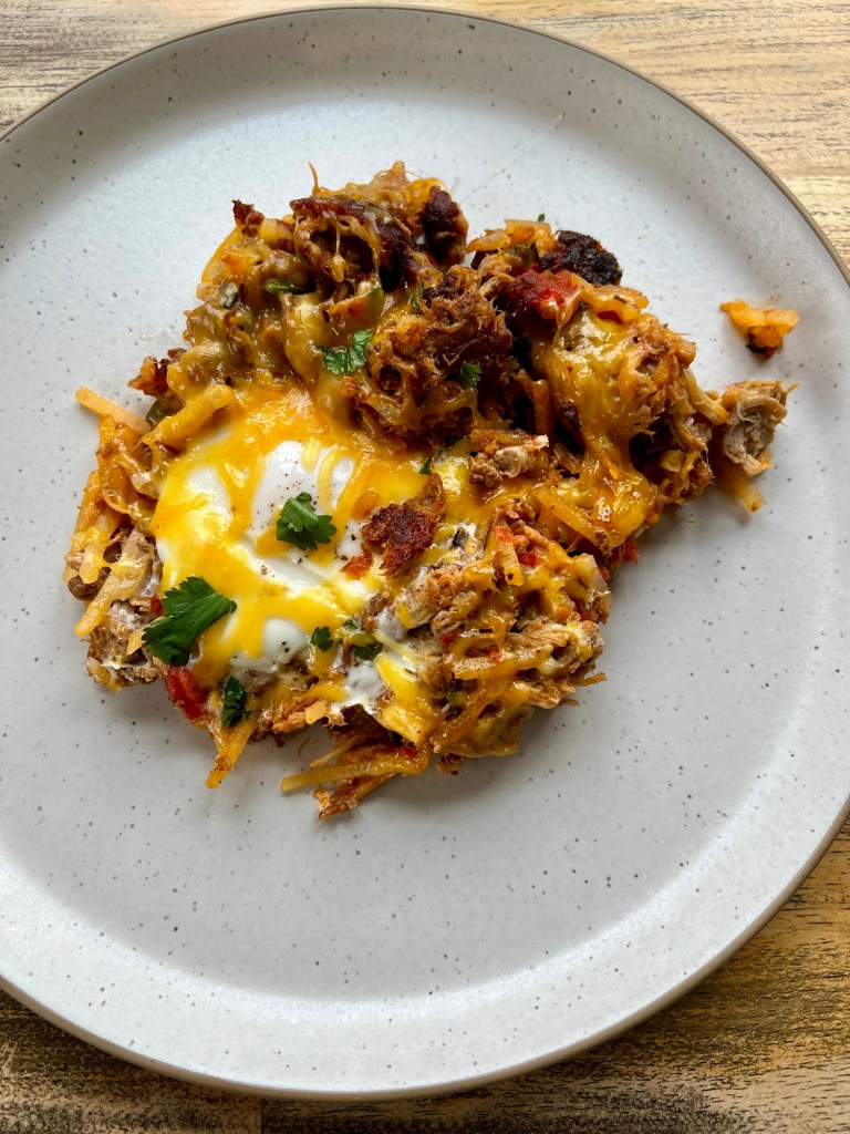 Pulled pork breakfast skillet on a white plate on a wooden table