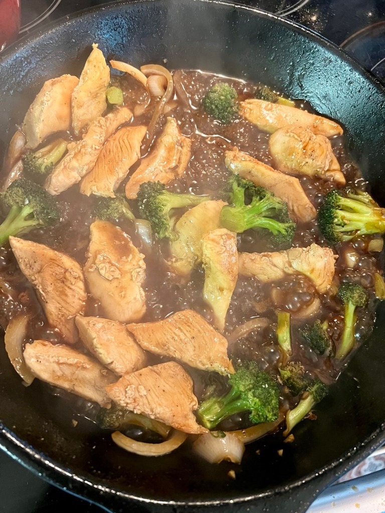 Chinese chicken and broccoli cooking in a skillet on the stove