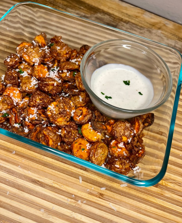 Carrot chips in a dish with some parmesan and parsley on top and ranch on the side