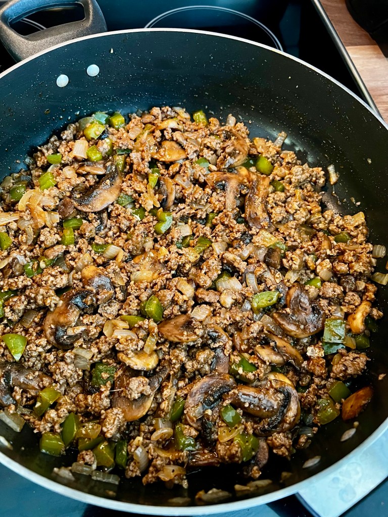 Ground beef, onion, garlic, green pepper, and seasonings in a skillet