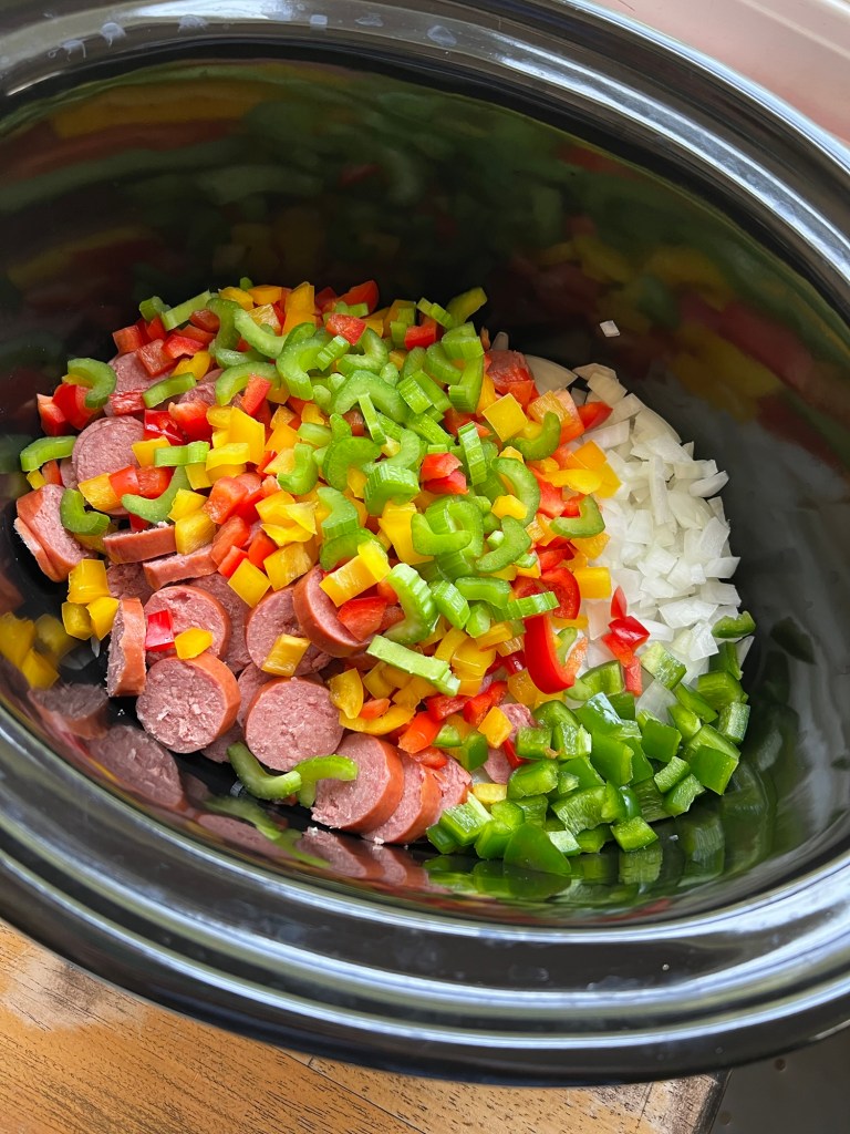 A bunch of fresh veggies and sausage in a crockpot