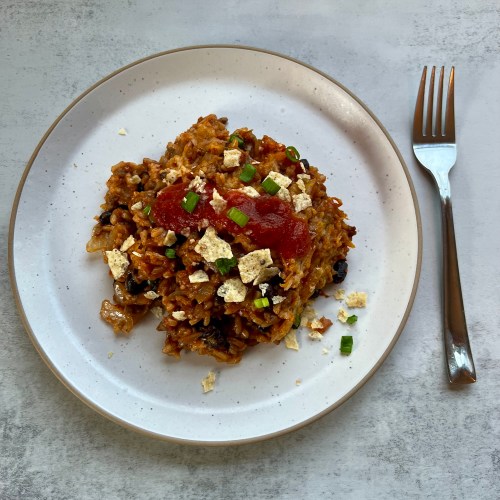 Burrito Bake on a white plate with a fork next to it on a countertop