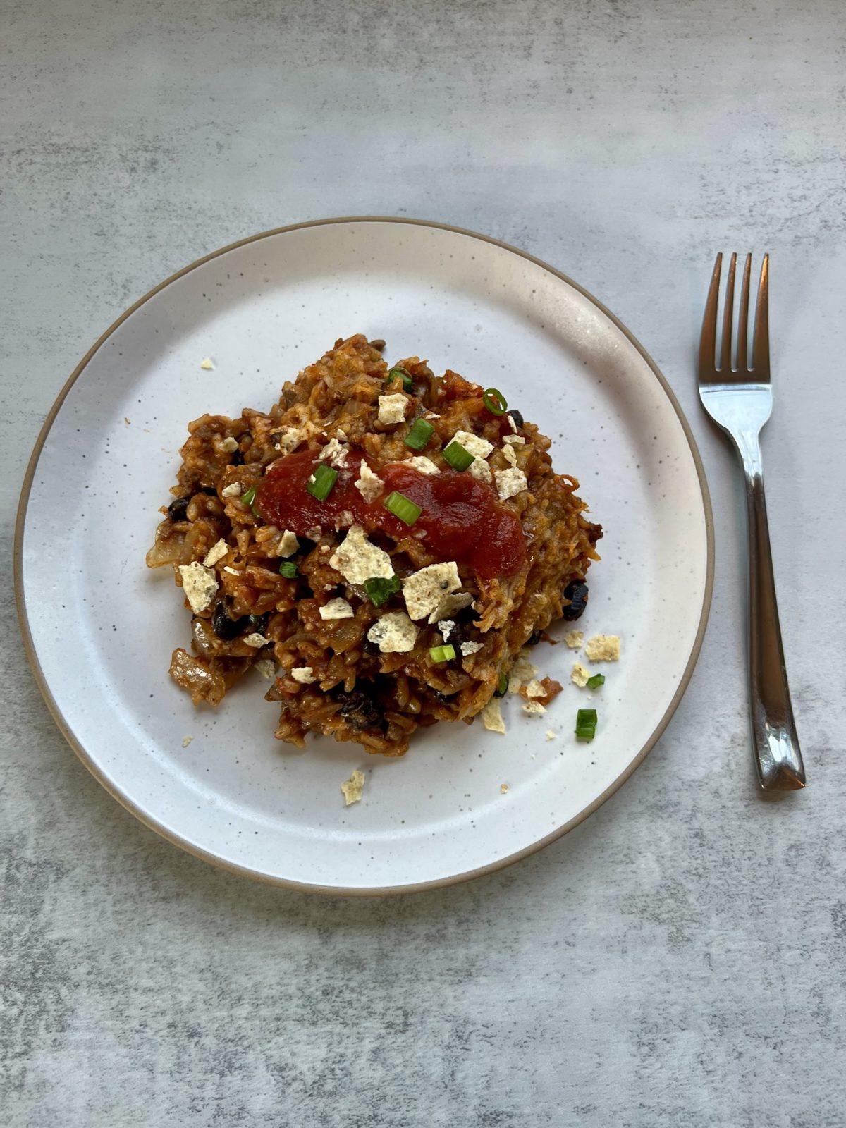 Burrito Bake on a white plate with a fork next to it on a countertop