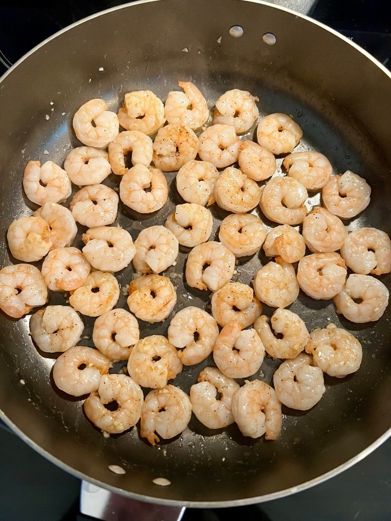 Shrimp cooking in a large skillet on the stove