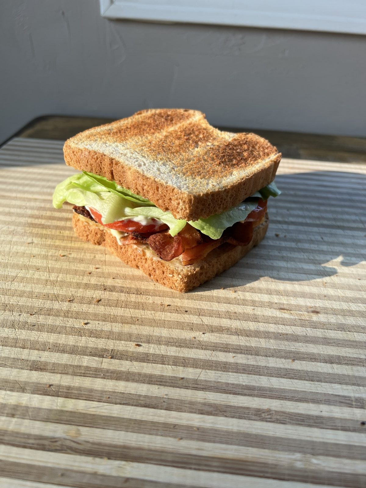 Ultimate BLT Sandwich on a wooden cutting board