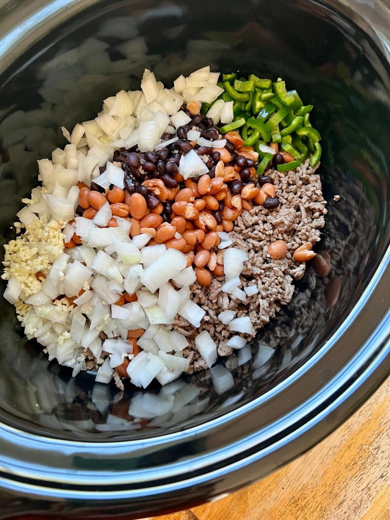 Large crockpot with beef and veggies inside before being cooked