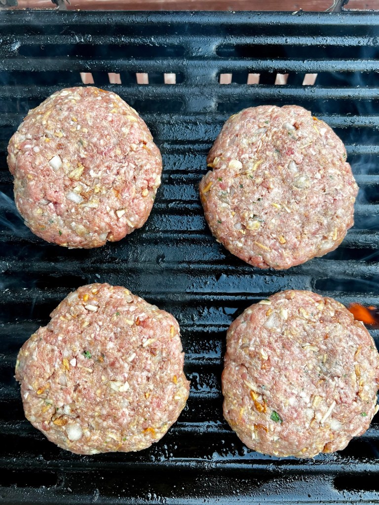 Four raw burgers on the grill