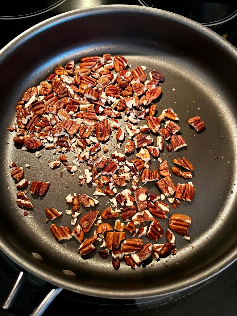 Pecans being toasted in a frying pan