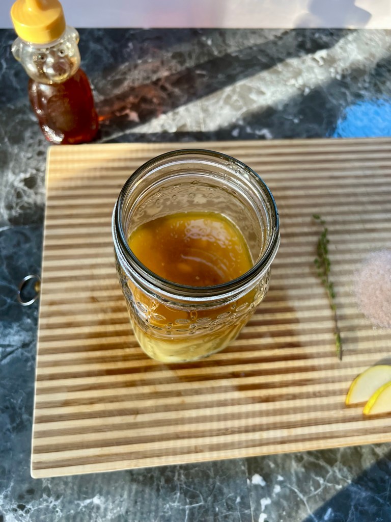 Mixture of pear bourbon smash ingredients in a mason jar on a wooden cutting board