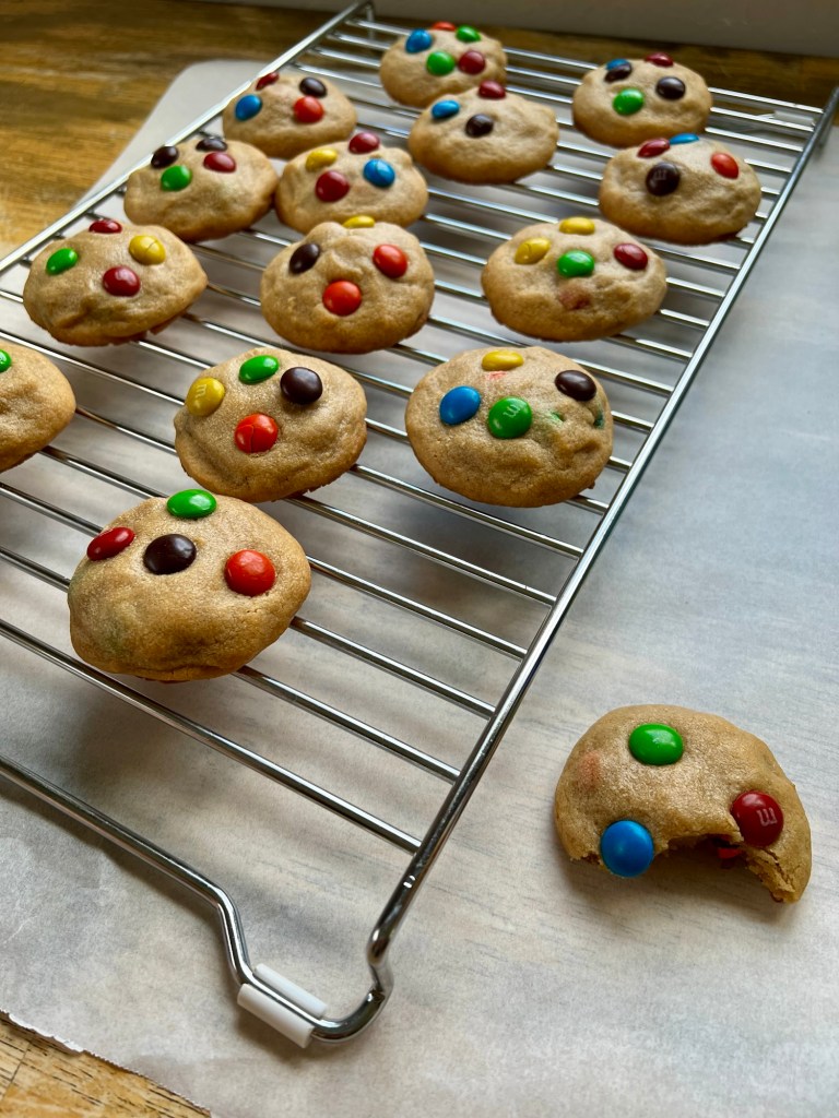 Cookies on a rack on top of some parchment paper, on a wooden table