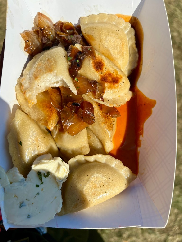 Pierogis from Pierogi Posse in a cardboard boat with some onion, sauce, and herb butter
