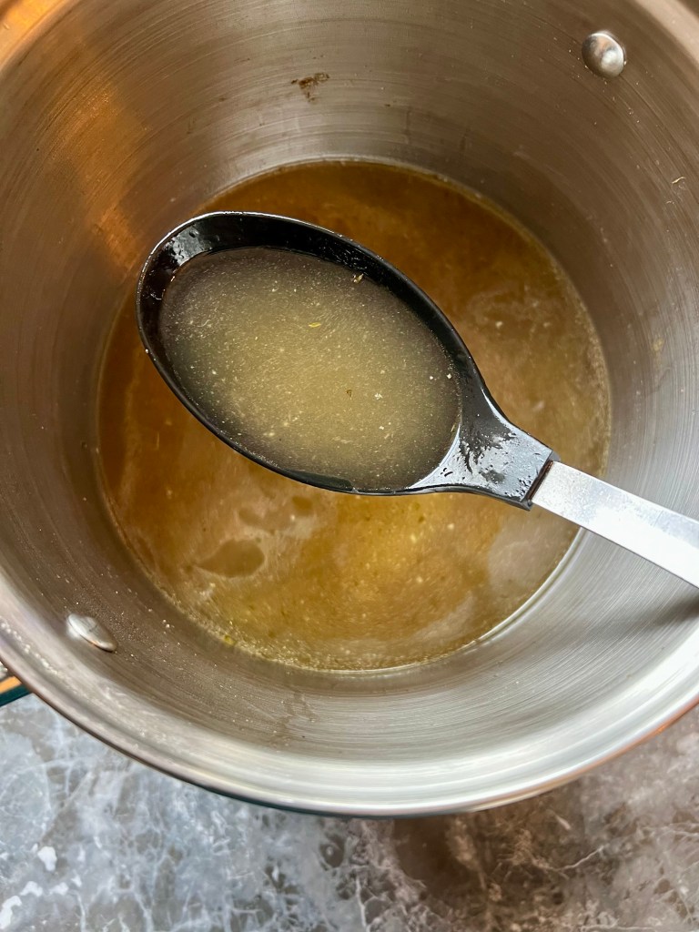 Homemade Turkey Stock in a large pot with a spoon scooping some out