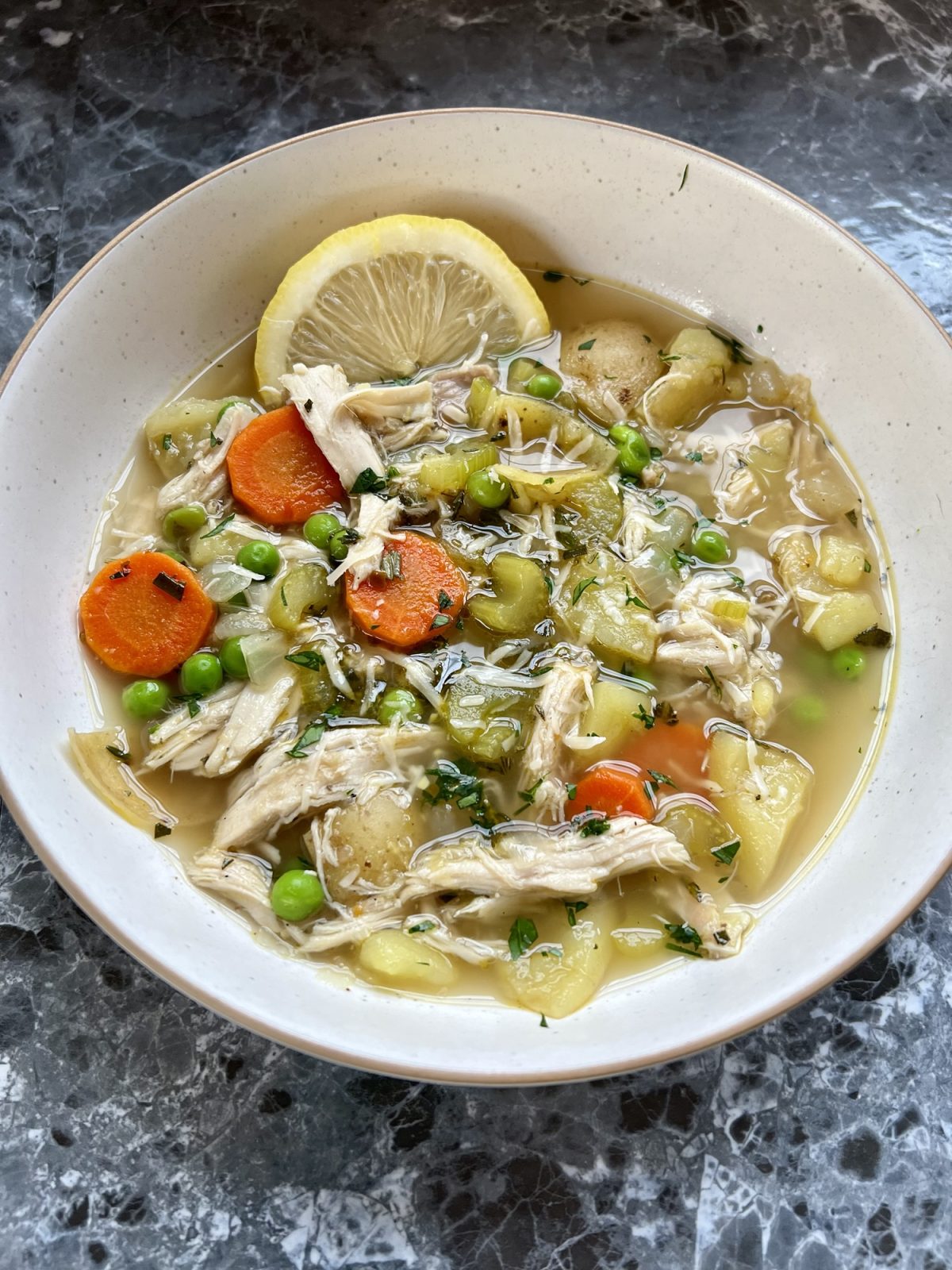 A white bowl filled with turkey stew with a lemon wedge on the side