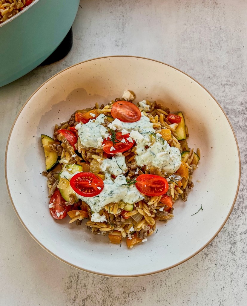 Mediterranean gyro bowl in a white bowl with a skillet filled with more right behind it