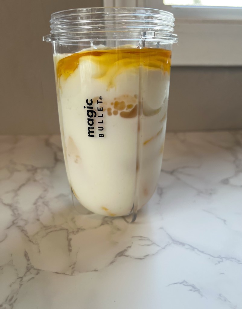 Ingredients for banana and frozen mango smoothie in a bullet cup before being blended