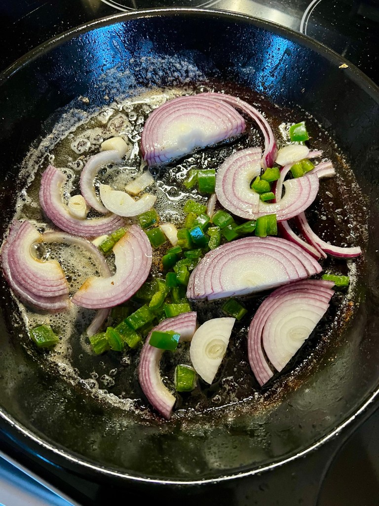 Red onion and jalapeno cooking in a pan on the stove
