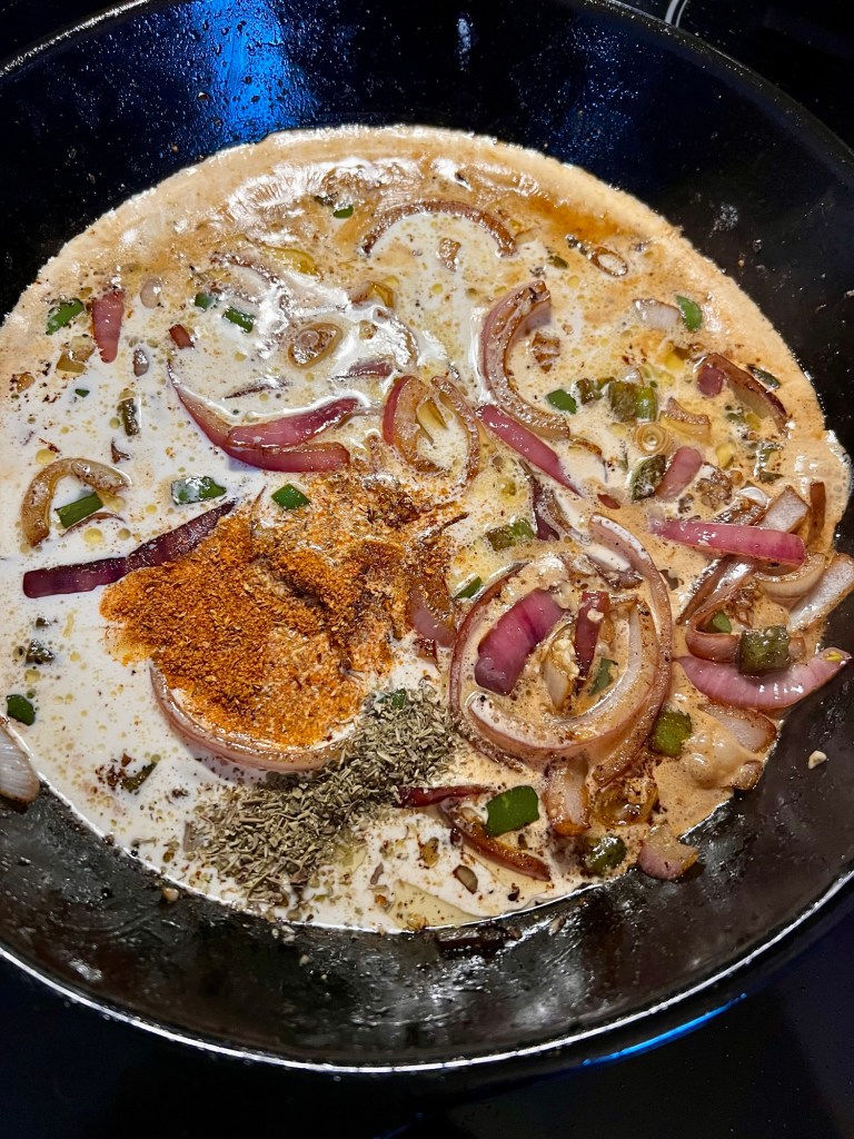 Veggies, spices, butter, and cream cooking in a skillet on the stove