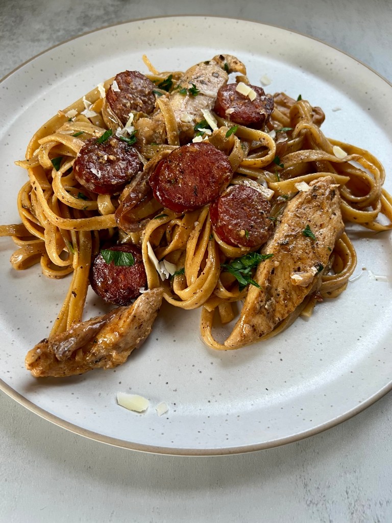 Sausage Chicken Cajun Pasta on a white plate on countertop