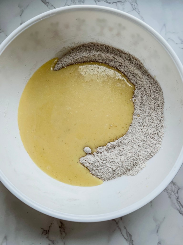Wet and dry muffin ingredients in a mixing bowl before being combined 