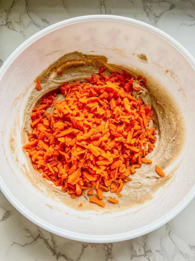 Ingredients for carrot crumble muffins in a large bowl