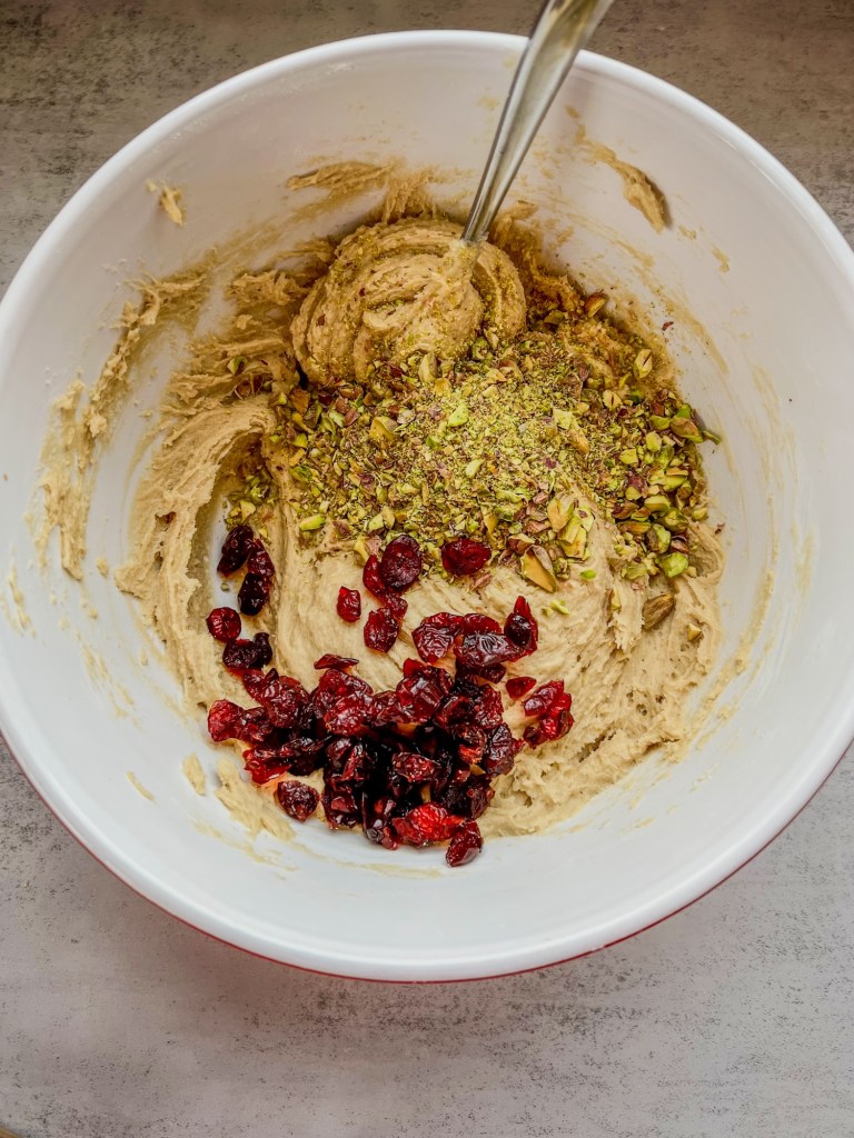 Pistachio and cranberry being mixed into cookie dough