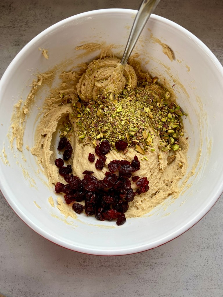 Pistachio and cranberry being mixed into cookie dough