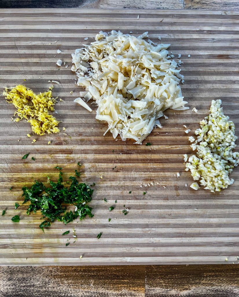 Parsley, lemon zest, garlic, and parmesan cheese on a wooden cutting board