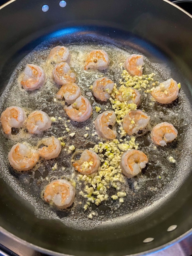 Shrimp cooking in a skillet with some garlic and butter