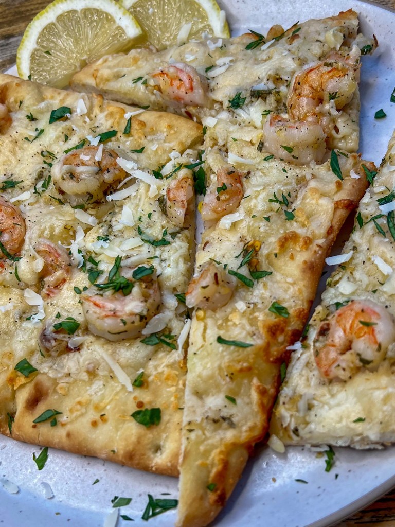 Flatbread cut into triangles on a white plate with some lemon on the side