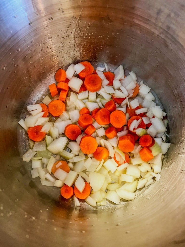 Onion and carrots cooking in a stockpot on the stove