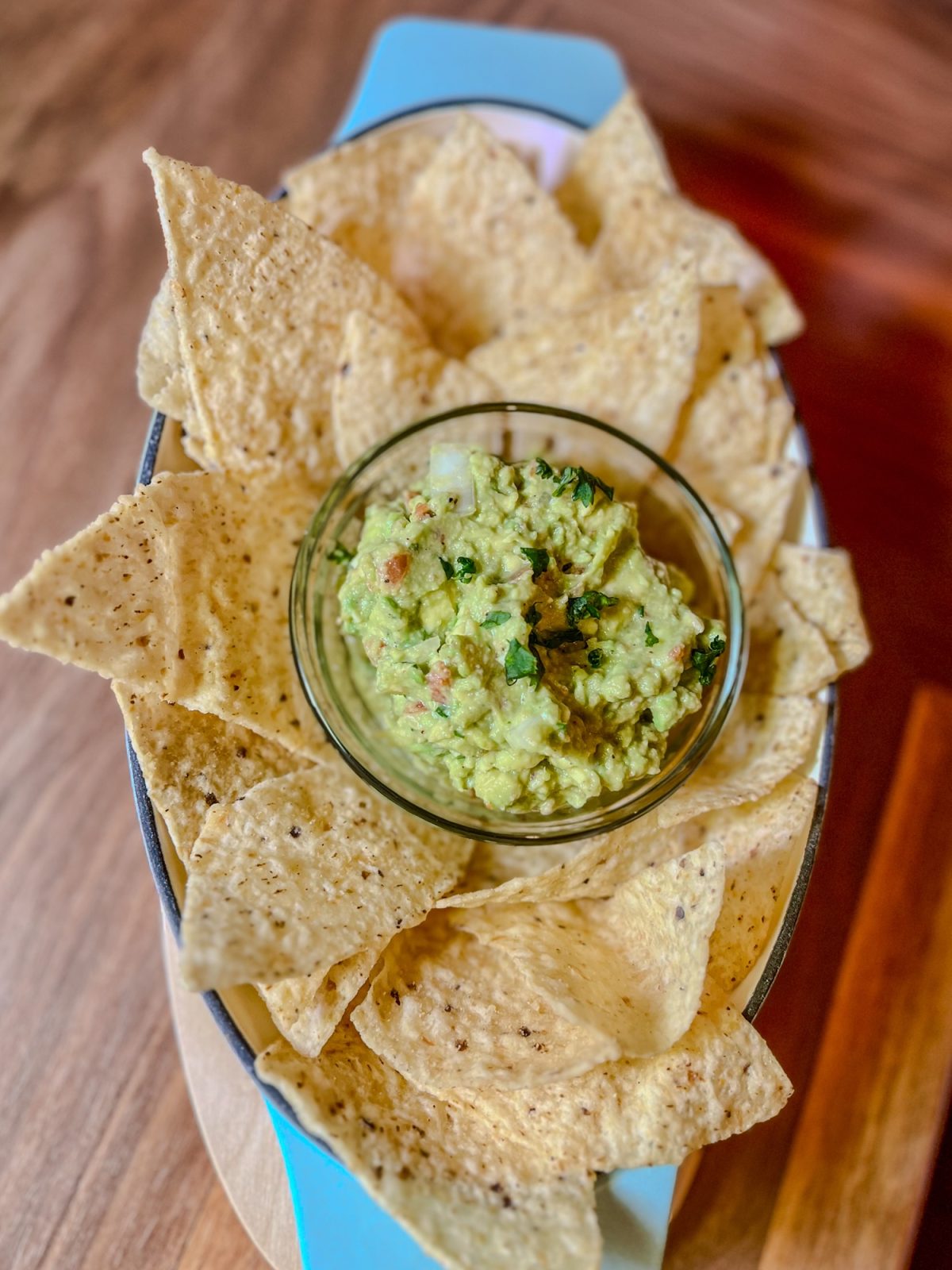 Guacamole in a serving dish with tortilla chips around it