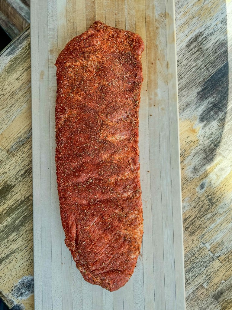 Ribs that have been rubbed with spices on a wooden cutting board