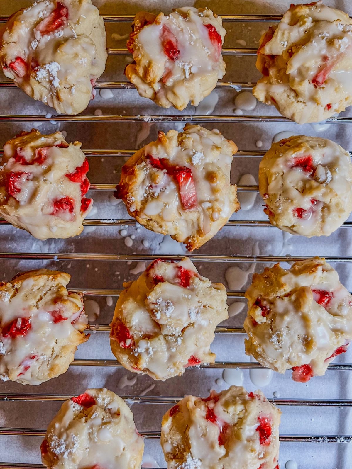 Strawberry scone cookies on a baking rack with parchment paper below