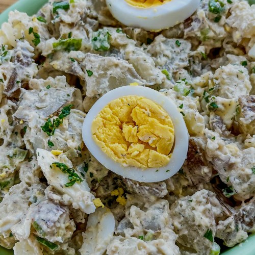 Rustic potato salad in a large green bowl on a wooden table