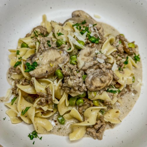 Beef stroganoff in a white bowl on a wooden countertop